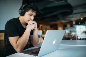 man looking at laptop with headphones on